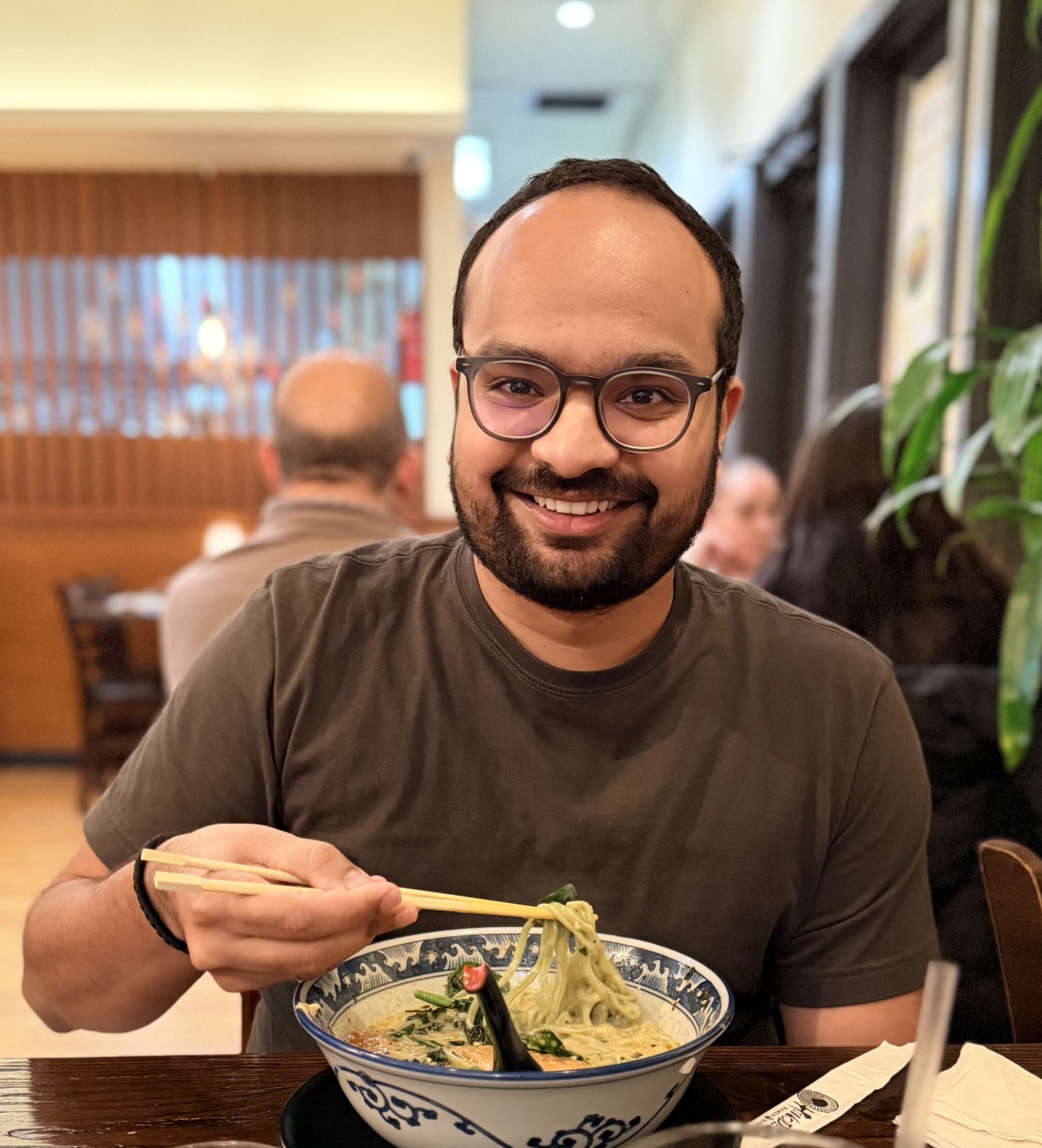 Shivam Lakhotia enjoying ramen with chopsticks at a restaurant